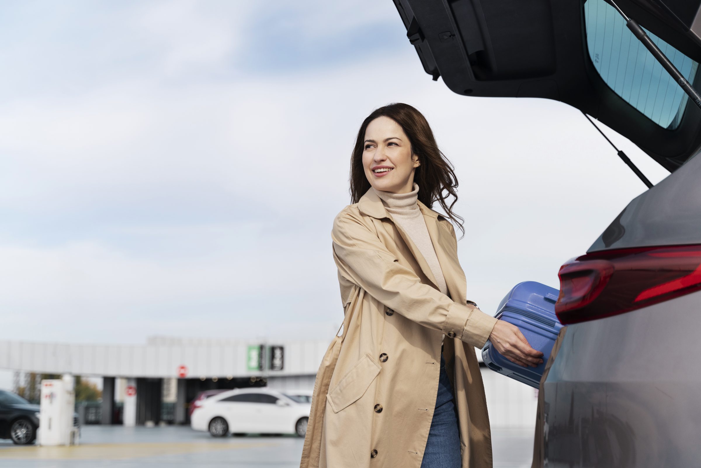 Woman loads case airport car park